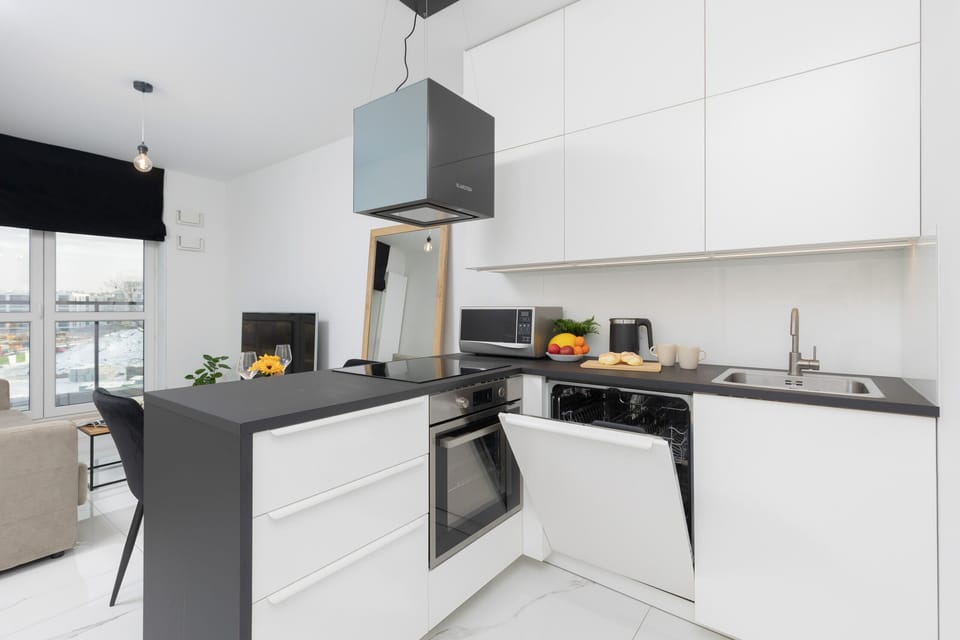 A modern kitchen with white cabinetry and integrated appliances.
