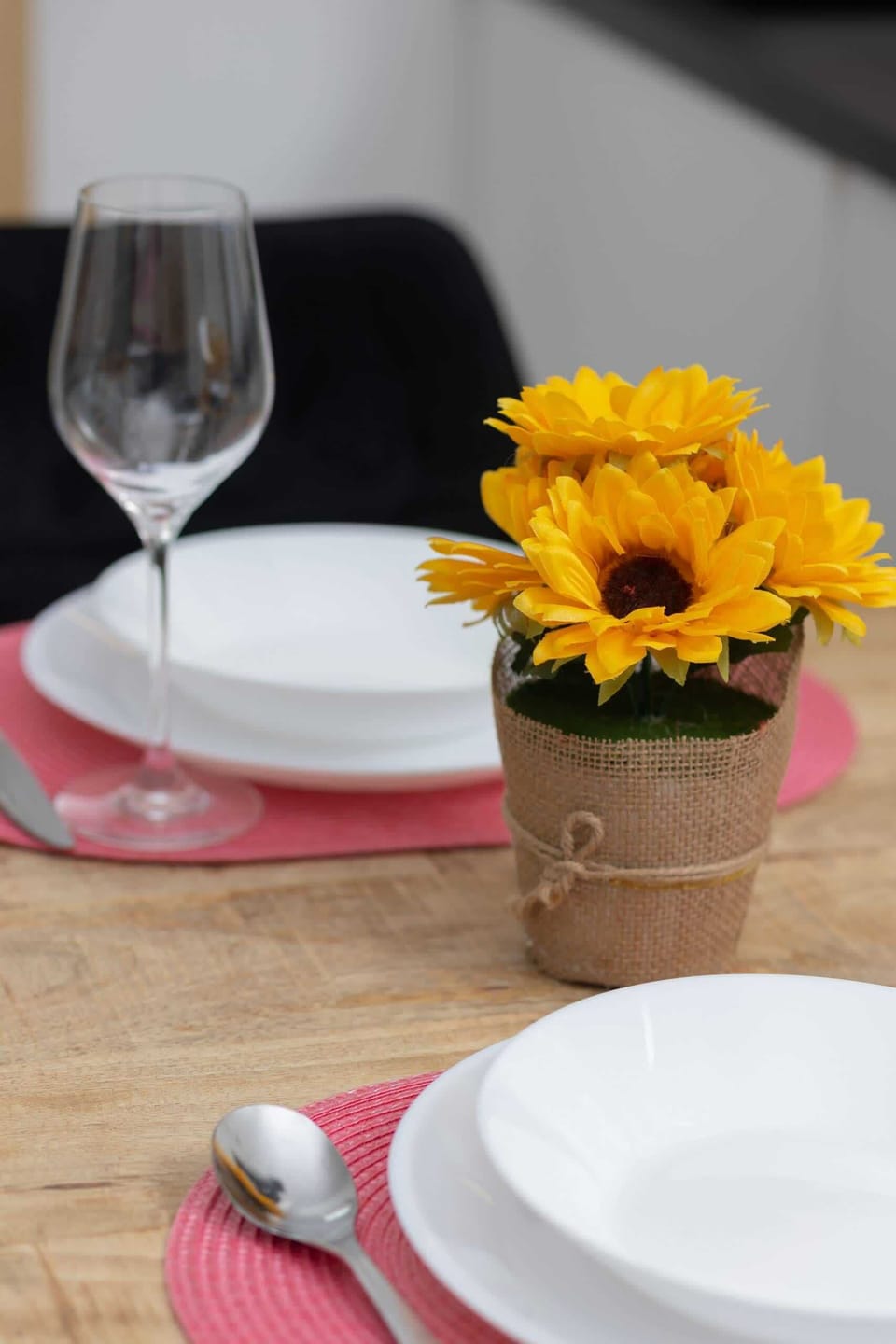 A close-up of a dining setup with a sunflower centerpiece.
