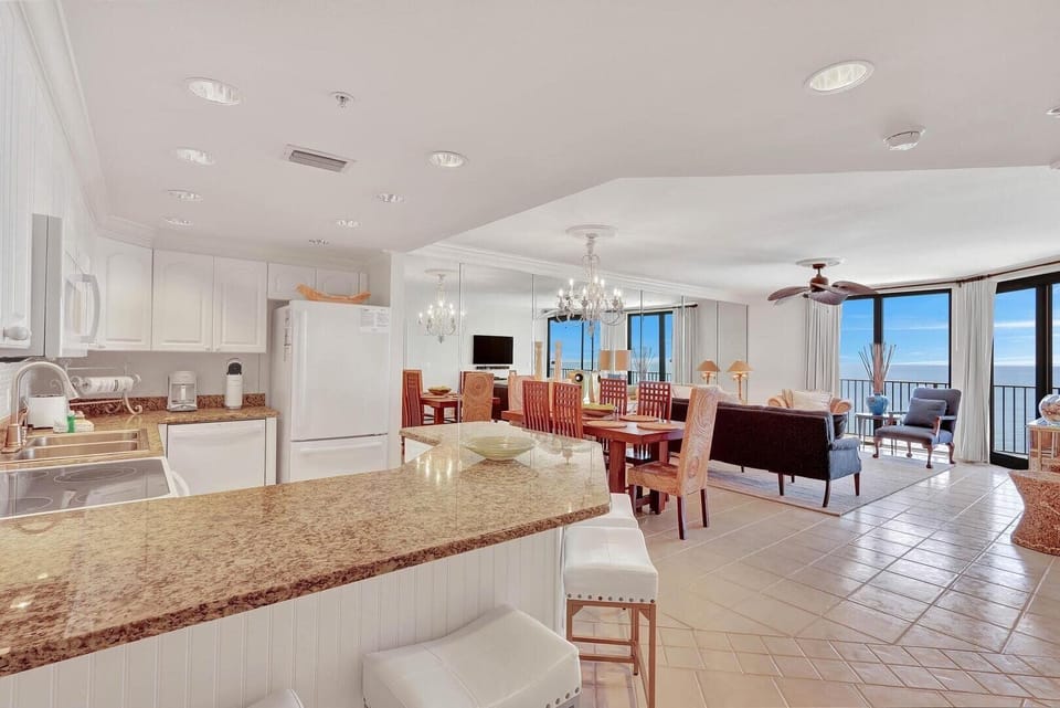 The kitchen, dining, and living areas flow together seamlessly, creating a spacious and inviting environment for gatherings and relaxation. Upscale stools provide additional seating for four at the bar.