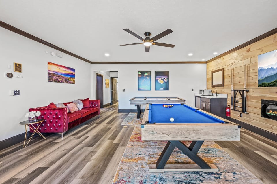 Family Room (Lower Level) : A perfect blend of fun and comfort with a pool table, air hockey, and 65-inch TV, framed by warm wood paneling and an electric fireplace 