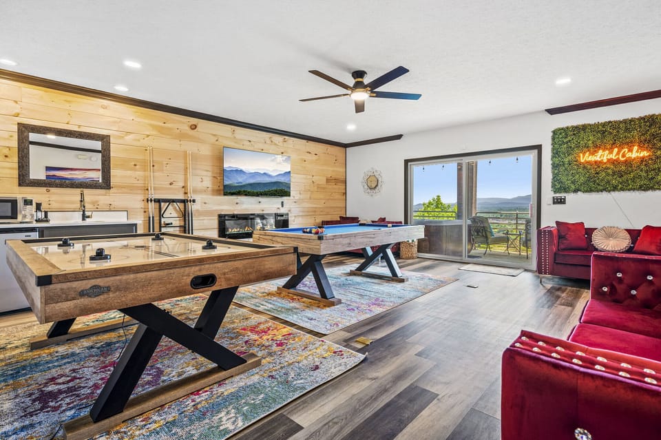 Family Room (Lower Level) A perfect blend of fun and comfort with a pool table, air hockey, and 65-inch TV, framed by warm wood paneling and an electric fireplace  