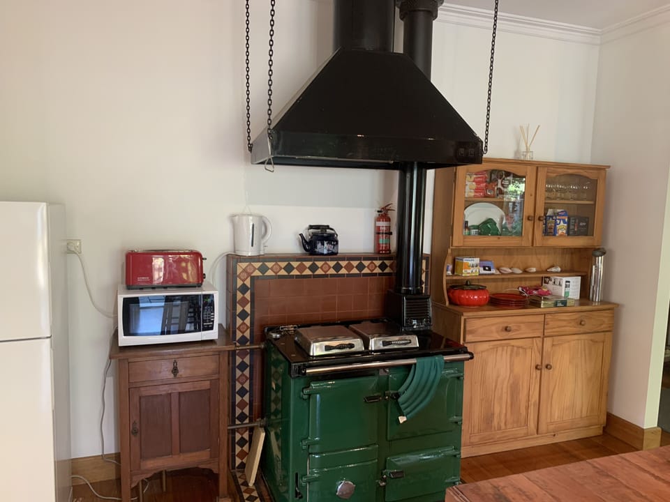 Country kitchen with fridge, microwave.  Wood burner stove not functional.