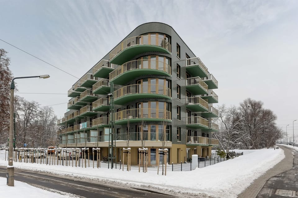 An exterior view of a modern building surrounded by snow and greenery.
