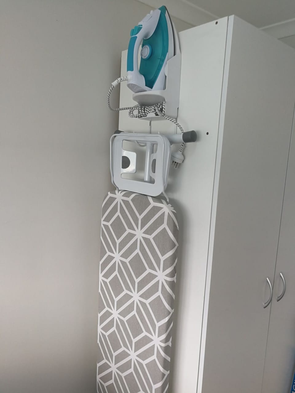 Steam iron and ironing board in laundry.