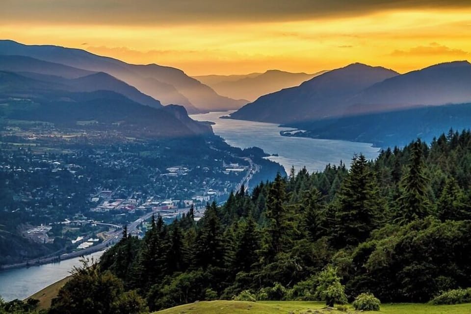 Sunset over the Columbia river framed by forested mountains.