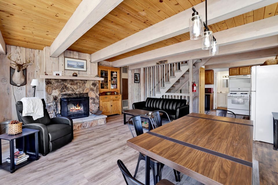 Cozy mountain living room with a stone fireplace, comfy seating, and smart TV—perfect for relaxing evenings, movie nights, and warm cabin vibes after outdoor adventures.