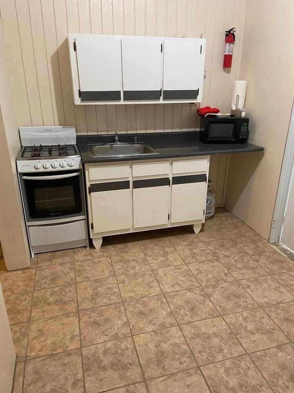 Full kitchen with a refrigerator, microwave, coffee maker, and cooking set. 