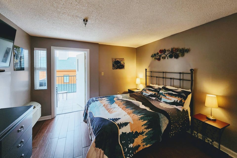 The primary bedroom offers a Queen bed, dresser, TV, private access to the balcony and bathroom