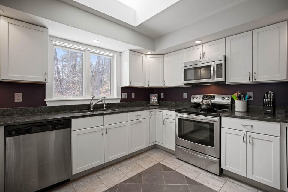 South side of the kitchen features dishwasher, sink, cups/glasses and a skylight