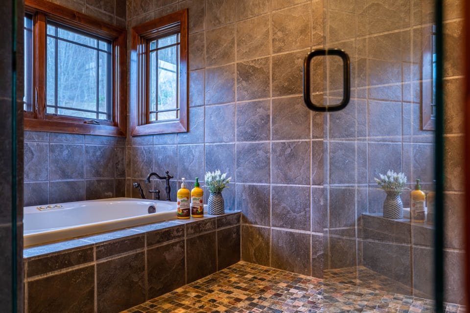 Soak away the day in this beautifully tiled bathroom, where a deep soaking tub sits beneath wood-framed windows overlooking the woods.