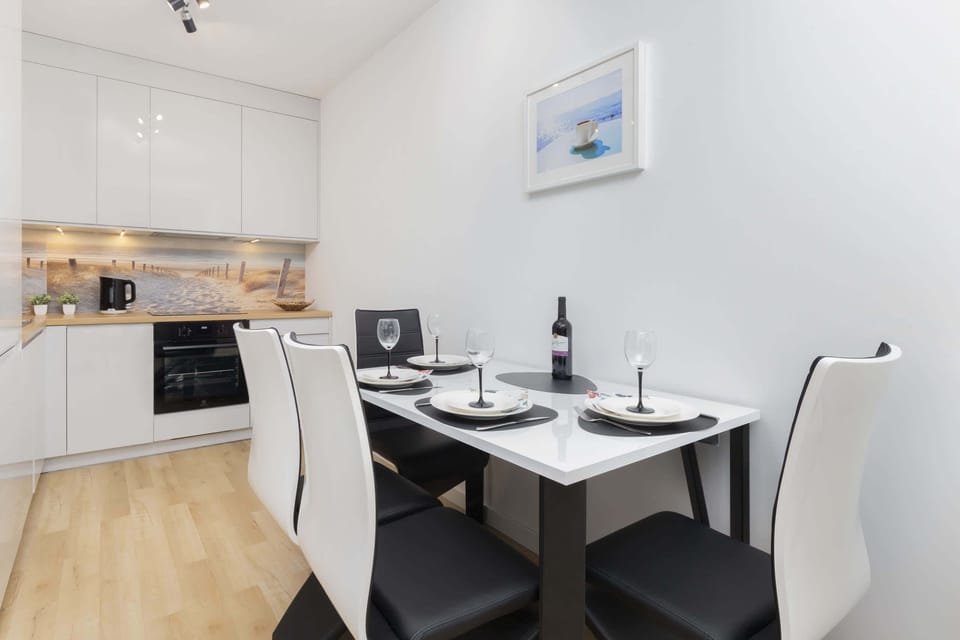 Dining area with a table set for four, featuring a clean, minimalist aesthetic and soft lighting.

