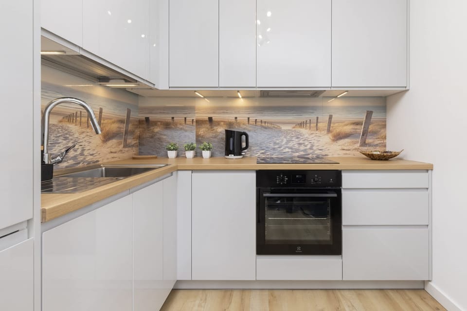 Fully equipped kitchen featuring white cabinets, light wood finishes, and modern appliances.


