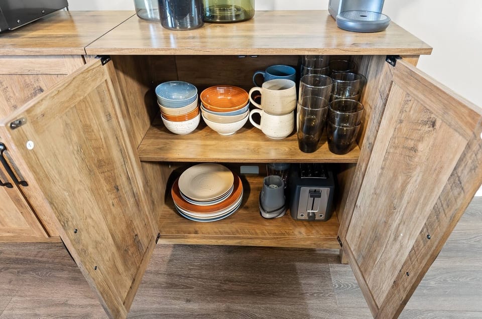 Colorful ceramic plates, cups, and bowls are located inside the drawer as well as a toaster and smoothie machine, perfect for a bright and early morning breakfast!