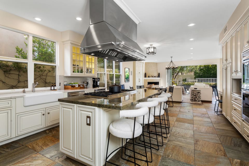 A spacious kitchen with a large island and bar stools & elegant cabinetry. 