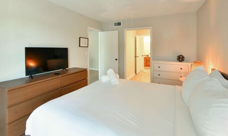 Bright king bedroom with side lamps, wall art, and window blinds