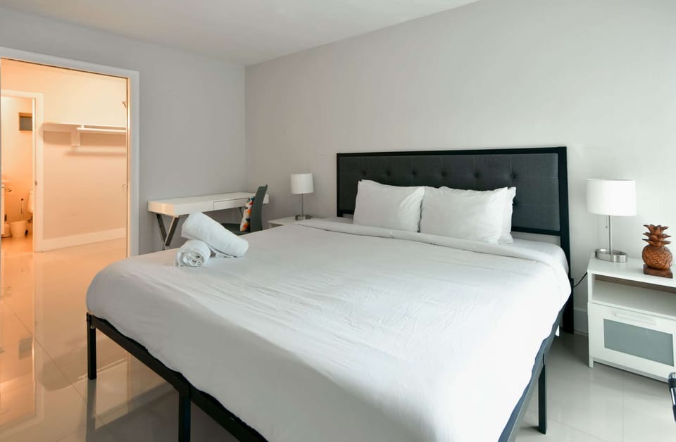 Bright king bedroom with desk, lamps, and open closet view