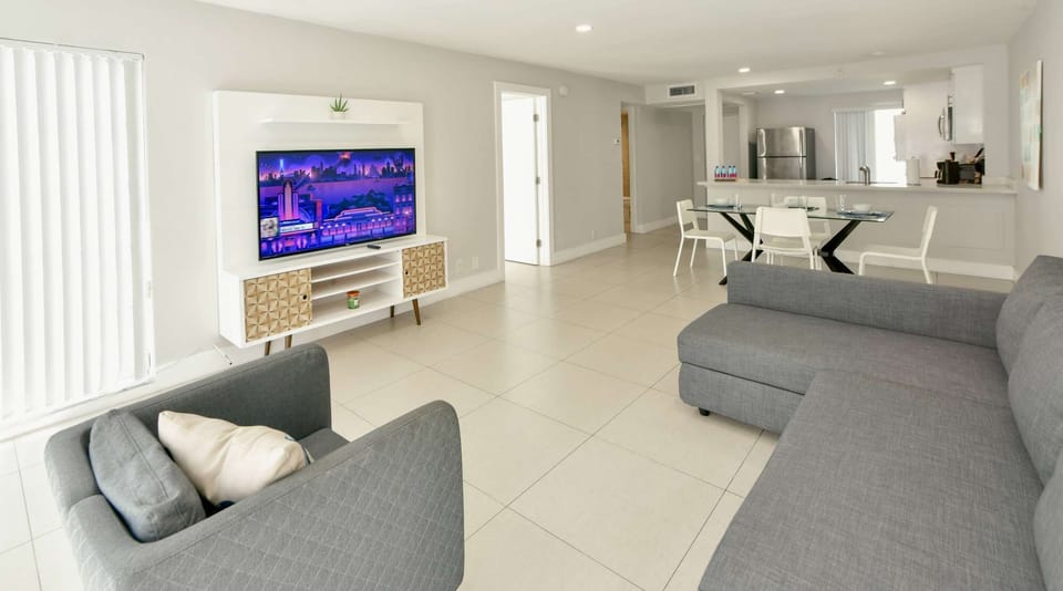 Open living room with sofa, chairs, TV stand, and dining area