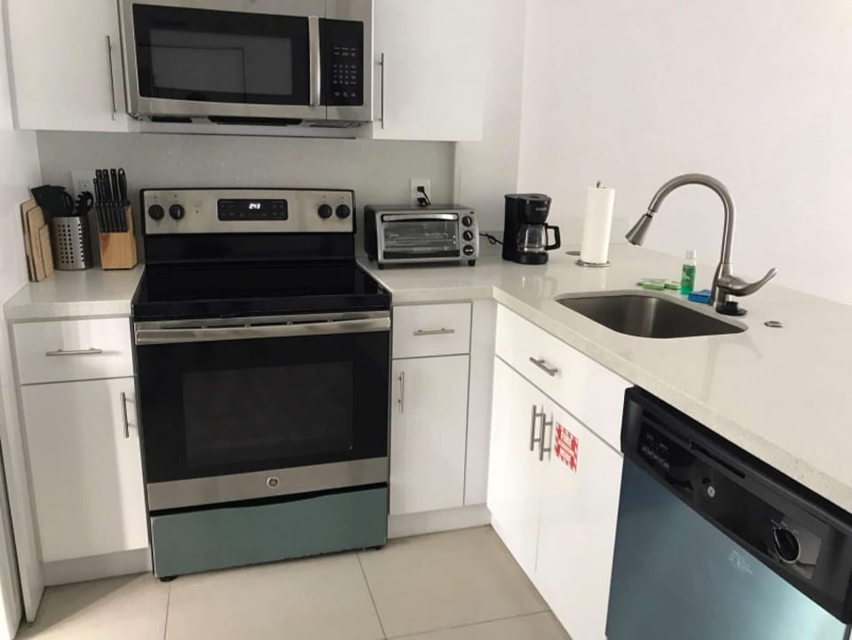 Bright kitchen with stove, sink, microwave, and coffee maker