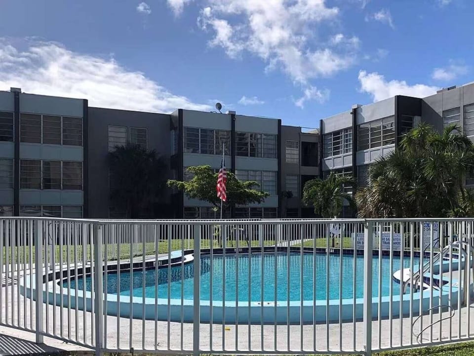 Fenced outdoor pool beside the building under a bright blue sky