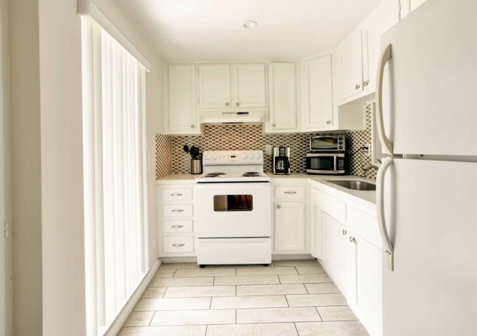 White kitchen with stove, fridge, microwave, and coffee maker