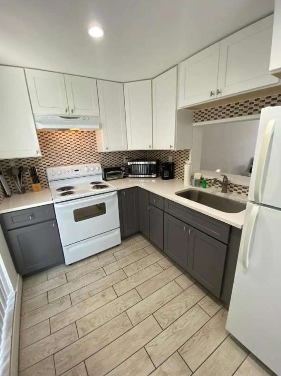 Bright kitchen with stove, sink, fridge, and cooking tools