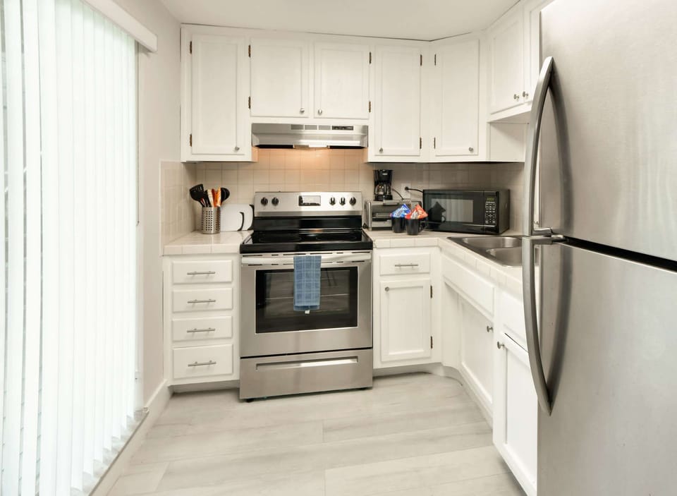 White kitchen with stove, sink, fridge, and coffee maker