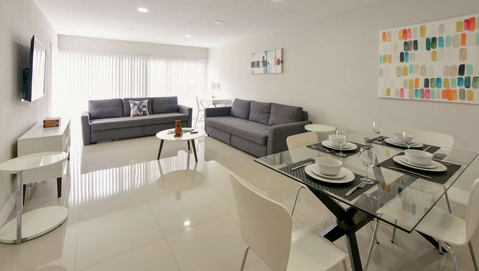 Open living and dining area with sofas, table, and wall art