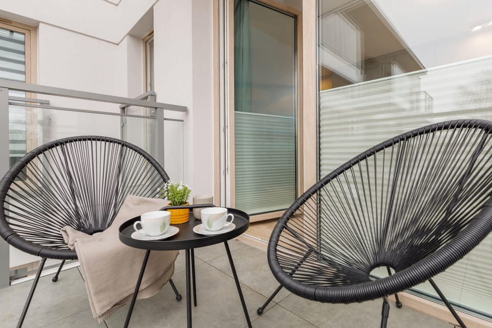 A cozy balcony setup featuring modern black chairs and a round coffee table.
