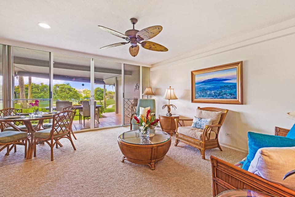 This spacious open-concept living room connects seamlessly to the outdoor lanai, creating the perfect setting for indoor-outdoor living with panoramic tropical views and a relaxed ambiance.