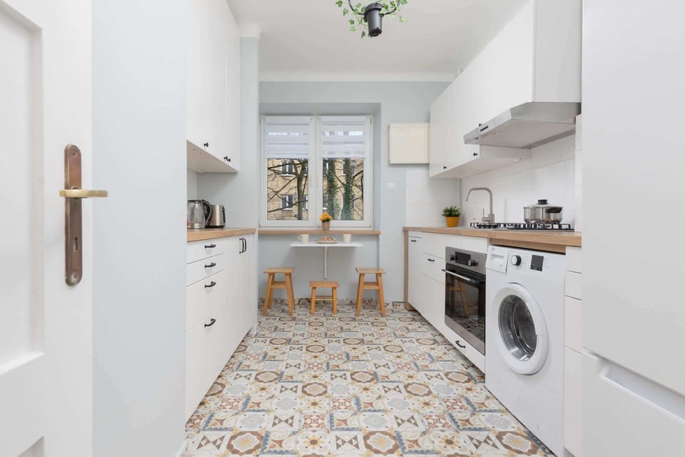 Compact kitchen area with modern appliances, including a washing machine, and a patterned floor design.

