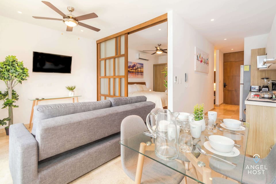 A wall-mounted flatscreen Smart TV, a cozy sofa that becomes a sofa bed for flexible sleep space