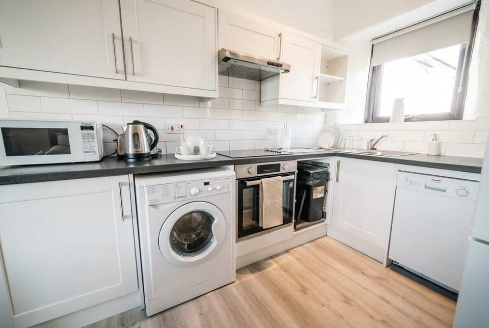 A sleek, space-saving kitchen fully integrated with a dishwasher, washing machine, and oven—ideal for long-term stays and home-cooked meals.
