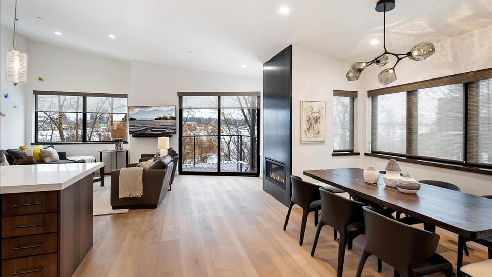 The grand master living room features a gas fireplace, rivew views, a balcony, open concept kitchen, living room, and dining area.