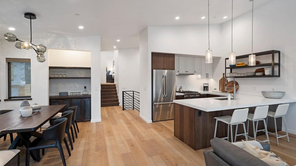 The grand master living room features a gas fireplace, rivew views, a balcony, open concept kitchen, living room, and dining area.