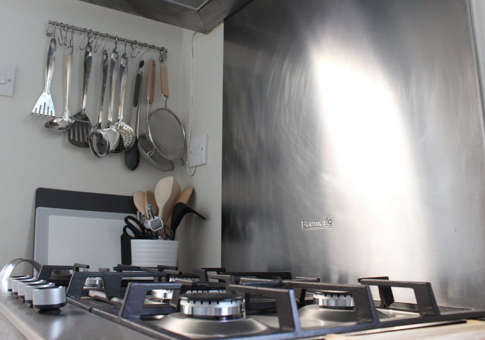 5 ring gas hob with lots of utensils and cooking appliances including air fryer.