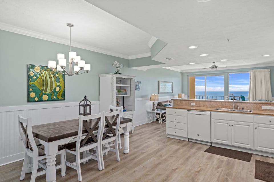 Open dining and kitchen area with ocean views and coastal decor.
