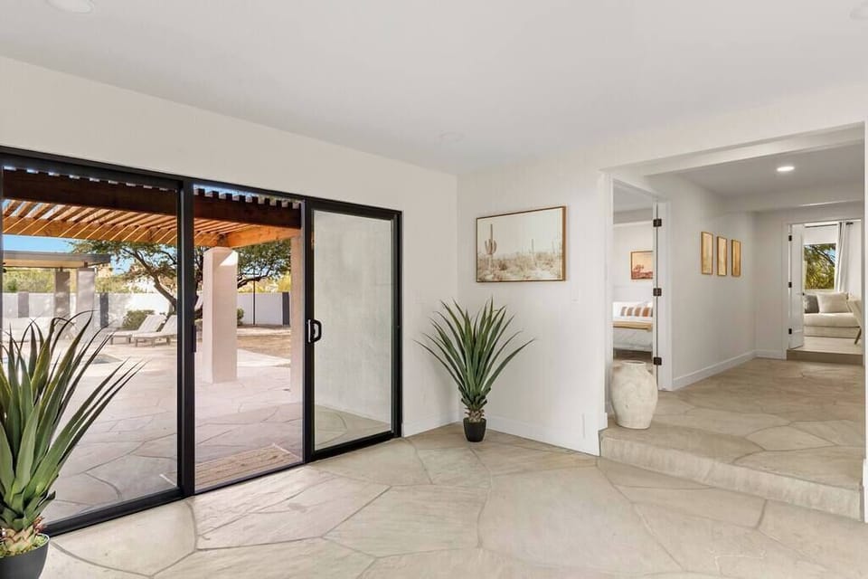 Bright entryway with large sliding glass doors opening to a shaded patio area.