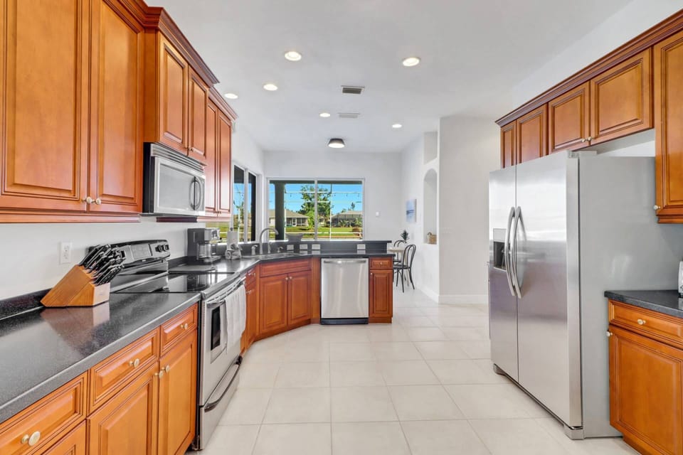 An eating bar with stools divides the kitchen from a breakfast nook, where you see the beautiful view behind the home.