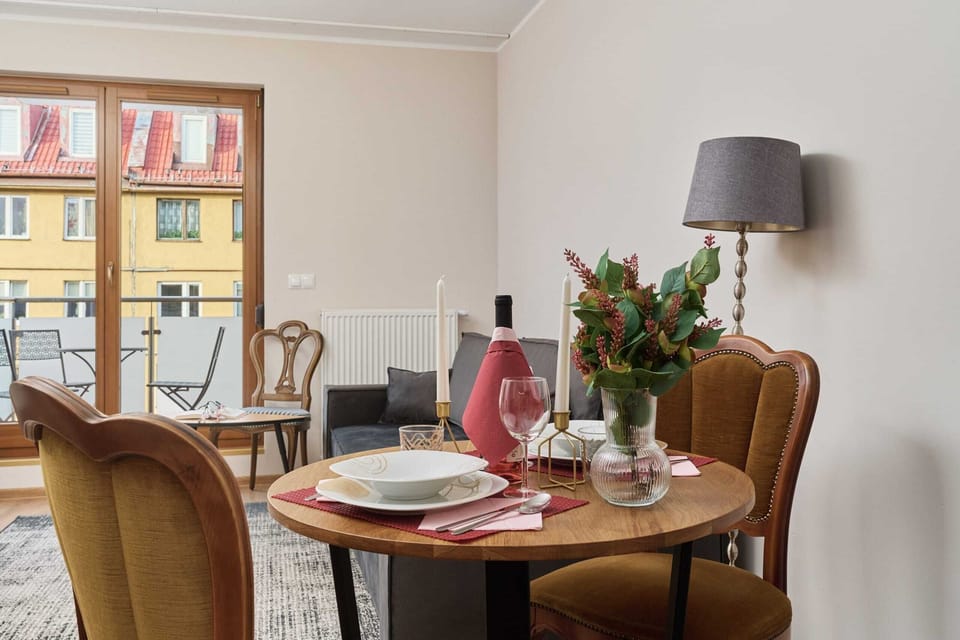 Dining table set for two, with a centerpiece and views of the outside architecture.

