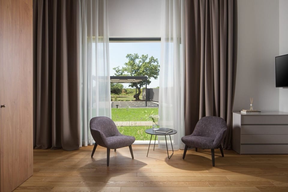 Seating area with armchair and coffee table, LCD TV and exit to the courtyard of Croatia luxury villa Art Zen in Istria