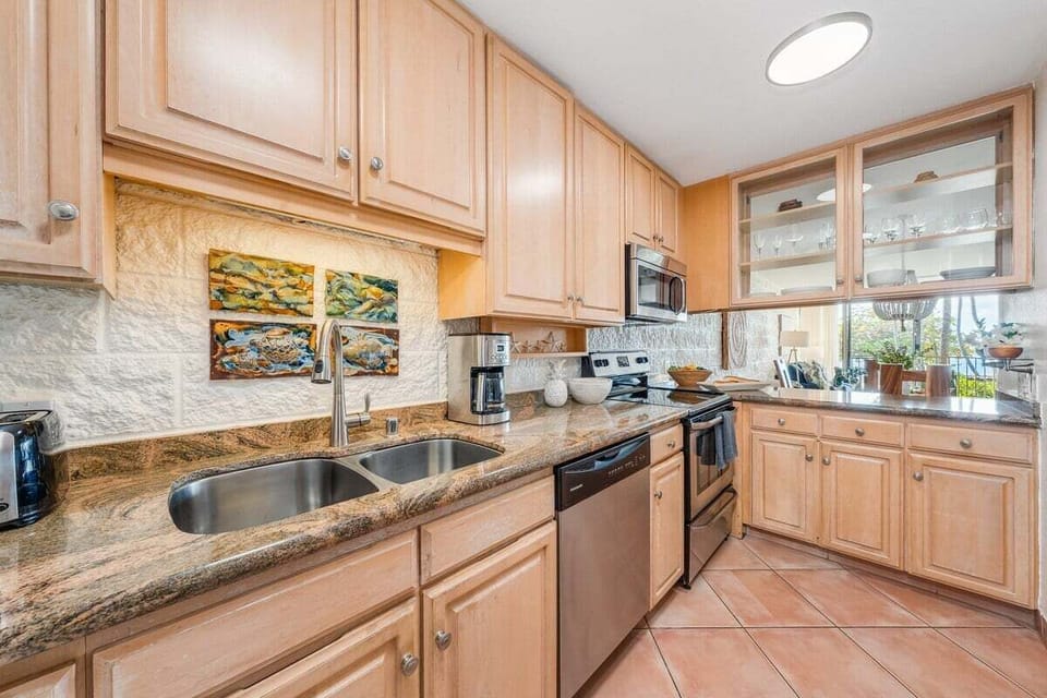 Fully equipped kitchen with granite countertops, stainless steel appliances, tiled backsplash, and ample storage for extended stays.