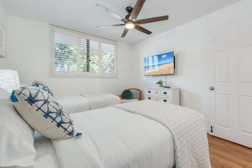Inviting bedroom with natural light, tropical artwork, and twin beds that may be converted to a king upon prior request.