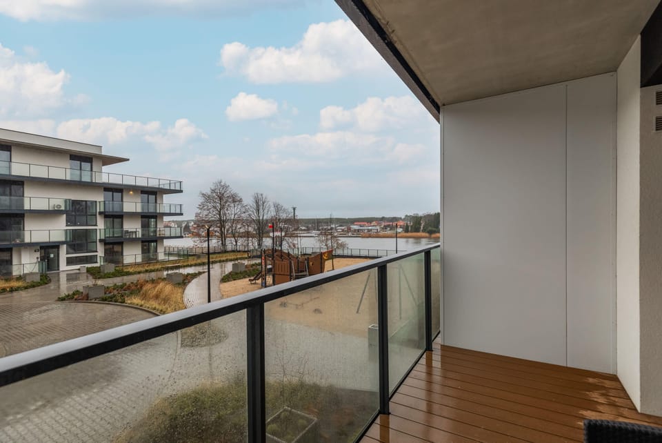 A balcony with a tranquil view of a modern residential area and green surroundings.

