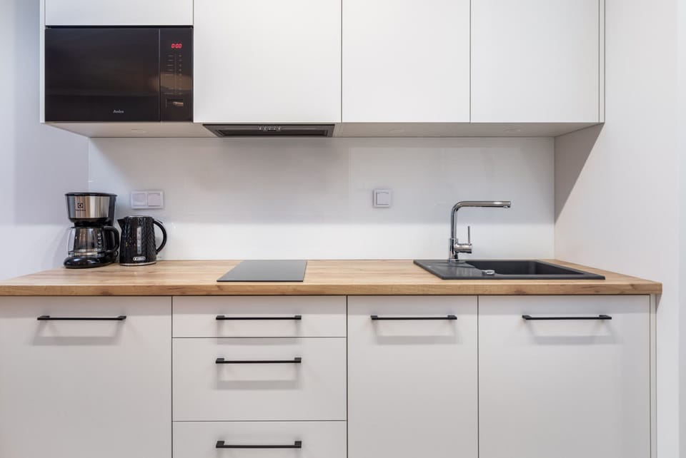 A clean and functional kitchenette with white cabinets and essential appliances.

