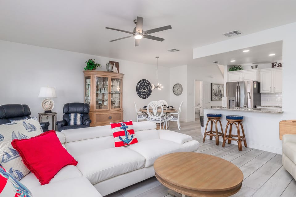 Relax in your spacious open-plan living area with comfortable seating, modern kitchen, and cheerful nautical touches throughout.