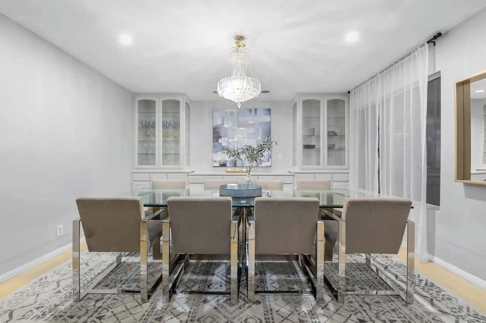 A beautifully designed dining area with 8 comfortable chairs, a sleek modern table, and lighting that adds an inviting warmth to the space. 