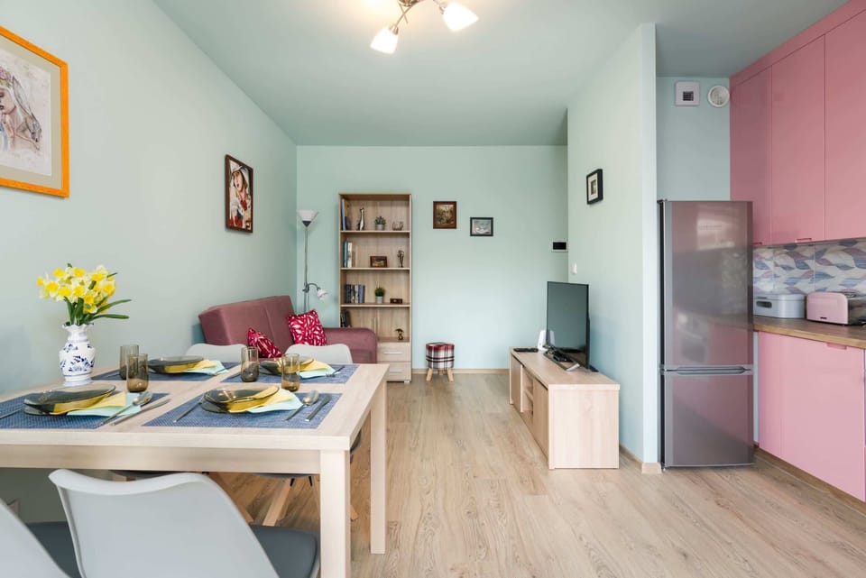 A spacious kitchen and living area with a retro-modern aesthetic, featuring pink accents.
