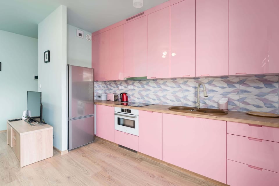 Another perspective of the kitchen, showcasing its sleek pink cabinets and patterned backsplash.
