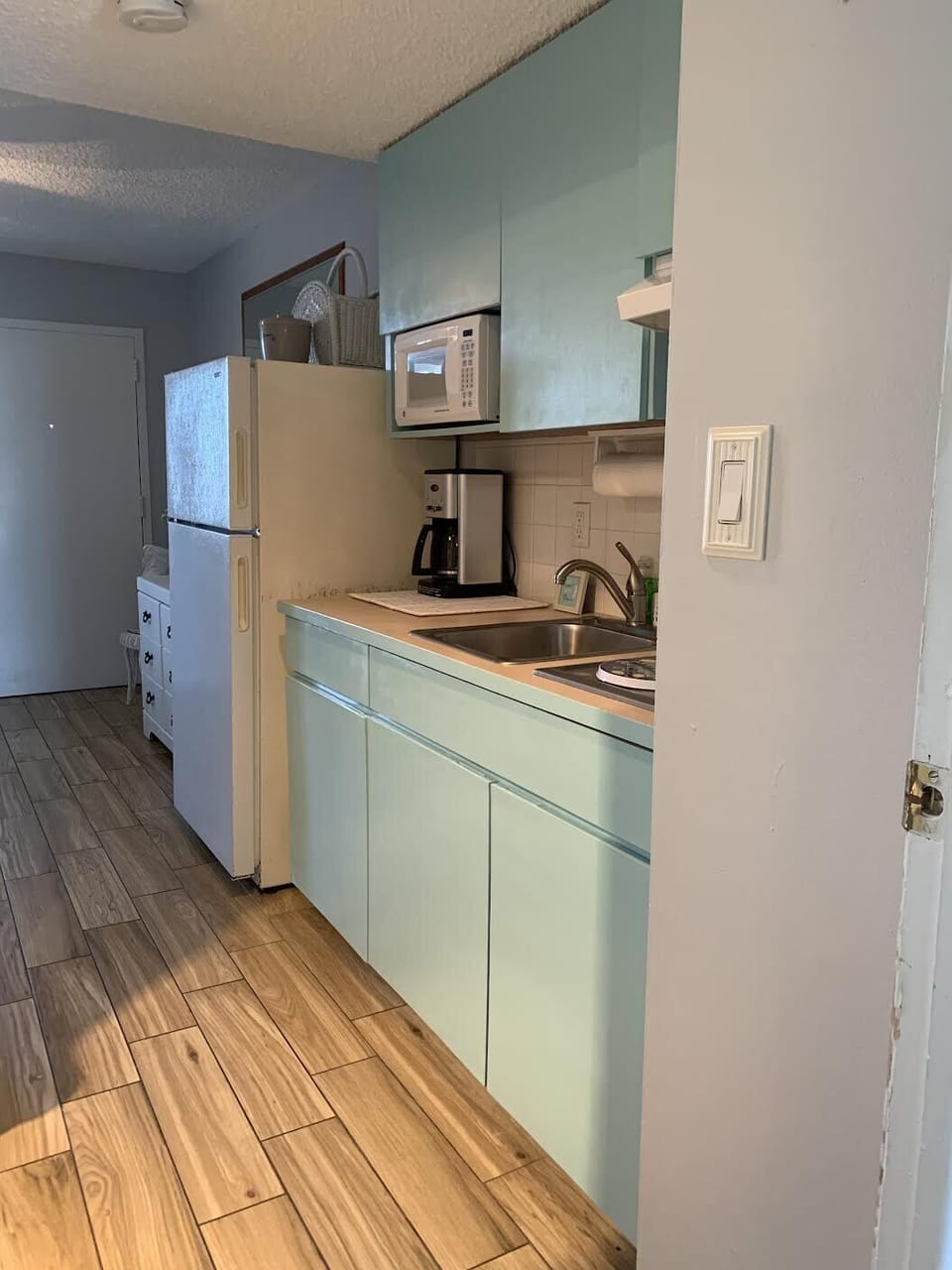 Kitchen w/ full refrigerator, stove top, microwave, coffee pot, plates, utensils