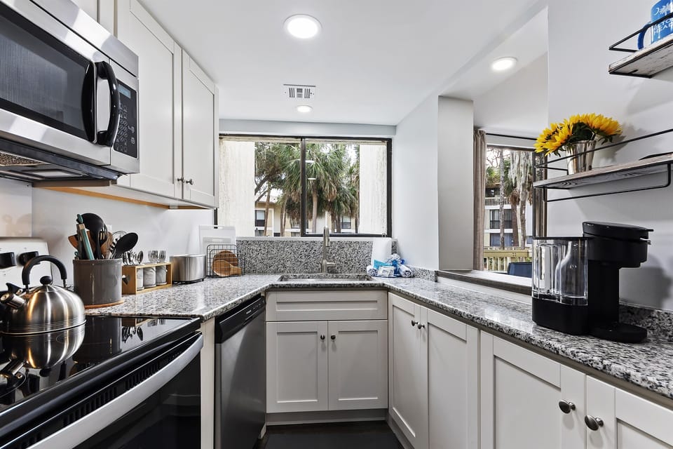 Indulge your culinary desires in this stunning white and stainless steel kitchen, fully equipped to effortlessly prepare delicious family meals.